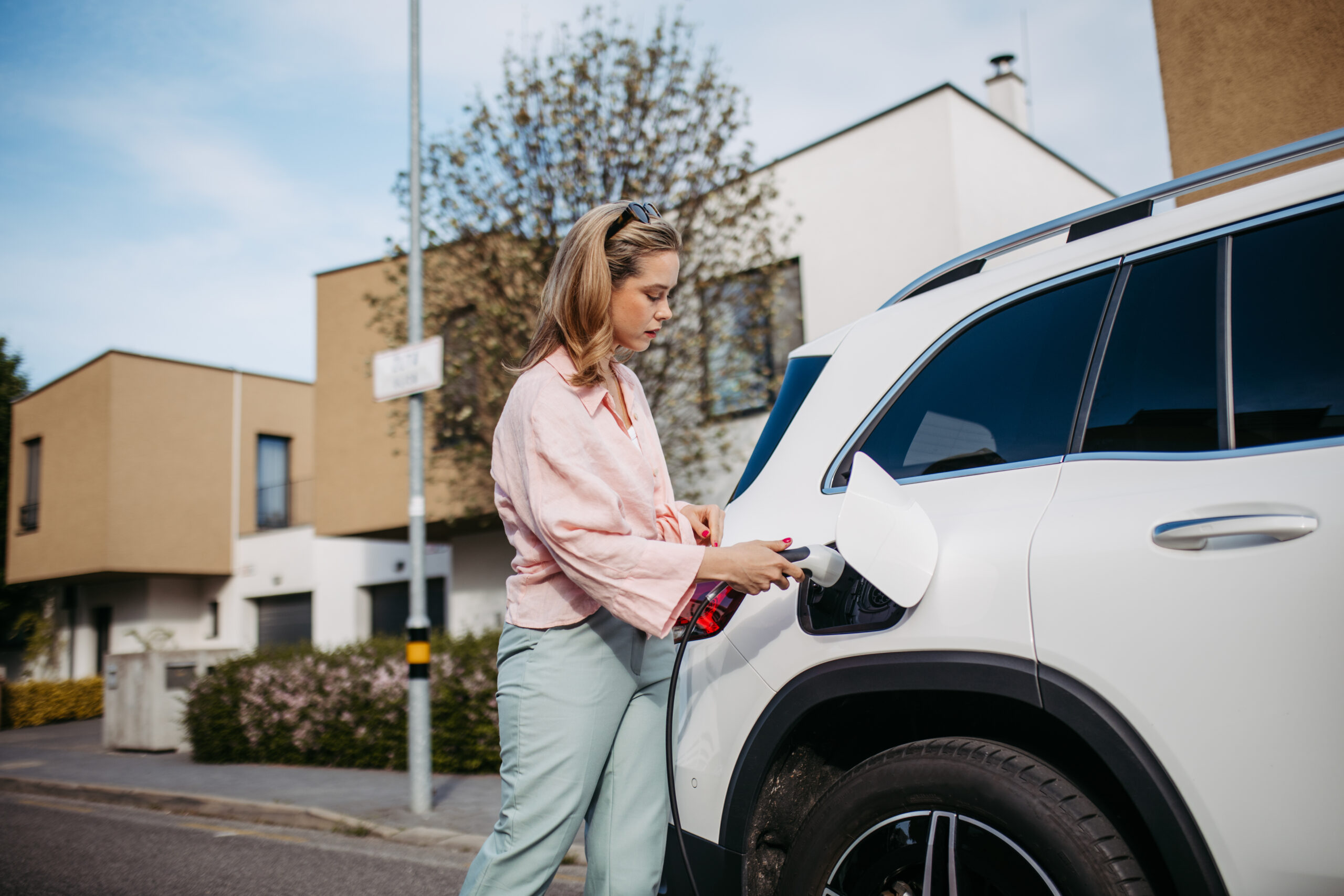 Woman charging her electric car, sustainable and economic transportation concept.